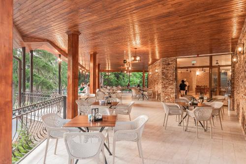 a restaurant with tables and chairs on a balcony at Hotel Cascada BAILE OLANESTI in Băile Olăneşti