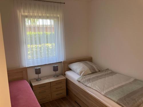 ein kleines Schlafzimmer mit einem Bett und einem Fenster in der Unterkunft Havelstern Ketzin, Ferienhaus Barsch in Ketzin