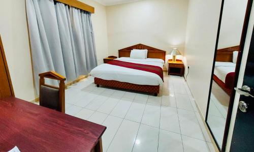 a bedroom with two beds and a table and a mirror at Al Ghadeer Hotel Apartment in Sharjah