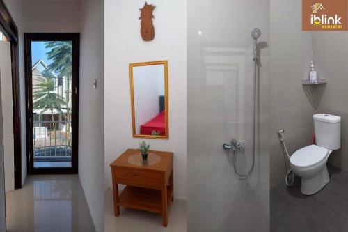 a bathroom with a shower and a toilet and a mirror at IbLink Homestay Family Homestay di Malang Full AC in Malang
