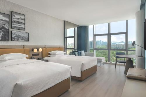 a hotel room with two beds and a table at Four Points by Sheraton Urumqi in Ürümqi