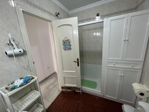 La salle de bains est pourvue d'une douche et d'une porte blanche. dans l'établissement CASA RAUSER, à Chipiona