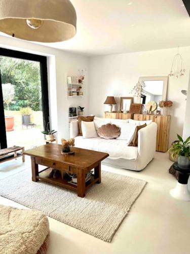 ein Wohnzimmer mit einem Sofa und einem Couchtisch in der Unterkunft Maison à l’orée du bois in Soustons