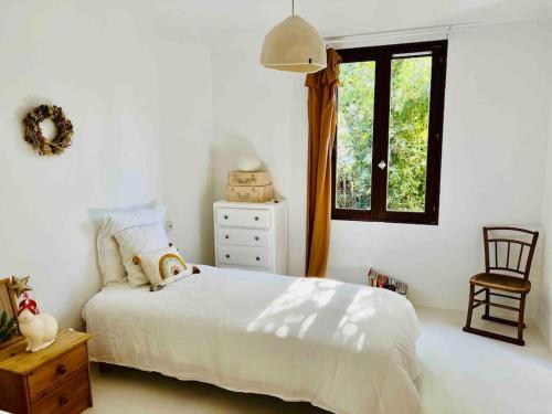 ein Schlafzimmer mit einem Bett, einem Fenster und einem Stuhl in der Unterkunft Maison à l’orée du bois in Soustons