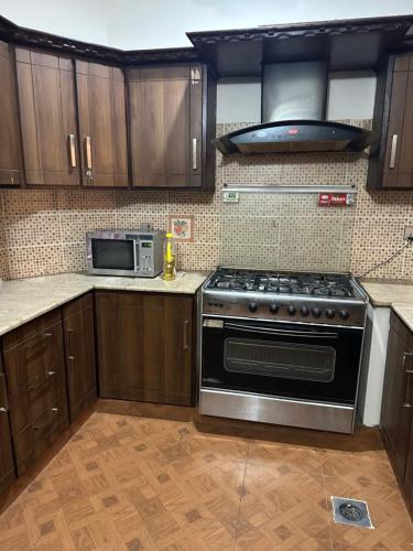 a kitchen with a stove and a microwave at Couples not allowed - Beautiful 10 marla Portion only for Families near Talwar Chouk in Lahore