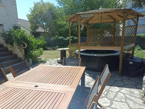 a patio with a table and a wooden gazebo at Suite avec billard et jacuzzi in Bergerac