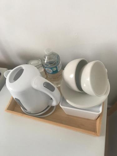 a shelf with two white dishes and a bottle of water at fAiRy Dell Guesthouse with cozy lockable rooms, tv, free tea tray, wifi & parking in Oakenshaw