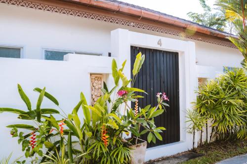 a white house with a black door and some plants at Layantara Villas in Layan Beach