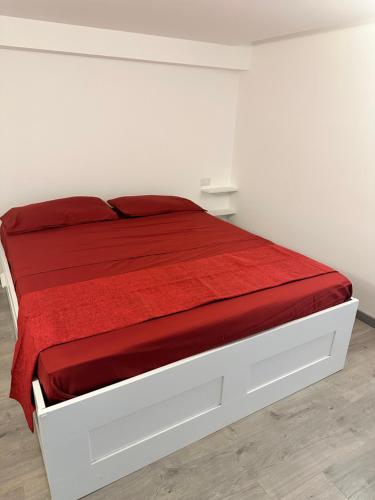 - un lit blanc avec des draps rouges et une couverture rouge dans l'établissement Appartamento Marco Simone, à Marco Simone