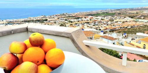 a bowl of fruit sitting on a table with a view of a city at Vintage Meson Ocean View in Adeje