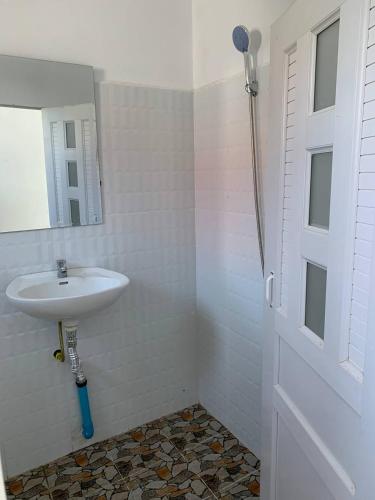 a white bathroom with a sink and a mirror at Home Daun Kam 1 in Kampot