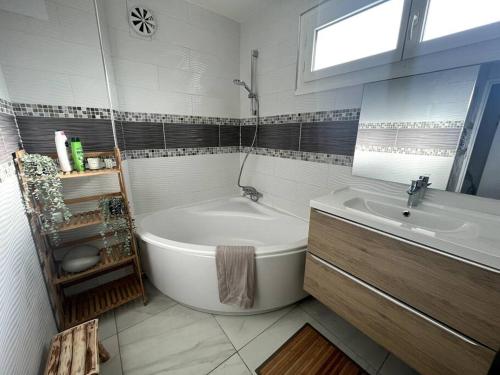 La salle de bains blanche est pourvue d'une baignoire et d'un lavabo. dans l'établissement Hana Home Spacieux t4 Calme Parking gratuit sur place, à Mantes-la-Jolie