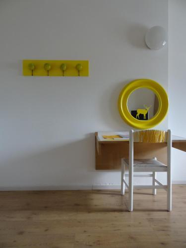 a white room with a white table and a yellow mirror at Hotel Giardino in Breno