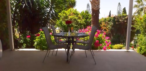 einen Tisch und Stühle auf einer Terrasse mit Blumen in der Unterkunft CORAL BAY suite Cyprus in Coral Bay