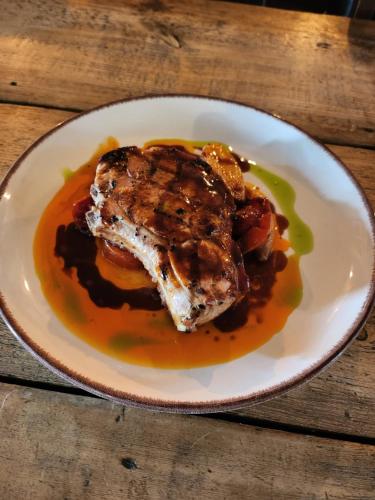 a white plate with a piece of meat with sauce at Kew Gardens Hotel in Kew