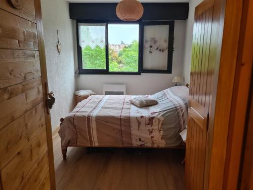 a small bedroom with a bed and a window at CHARMANT T2 de MONTAGNE à la STATION DES ROUSSES AVEC BALCON ET GARAGE in Les Rousses