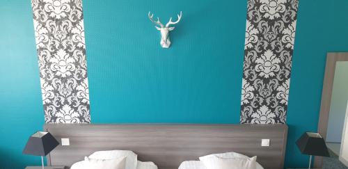 a bedroom with a bed with a deer head on the wall at Hôtel Le Rohan Charme et Caractère in Pontivy