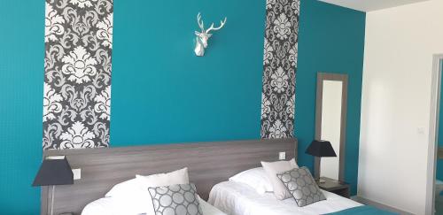 a bedroom with a blue wall and a bed at Hôtel Le Rohan Charme et Caractère in Pontivy