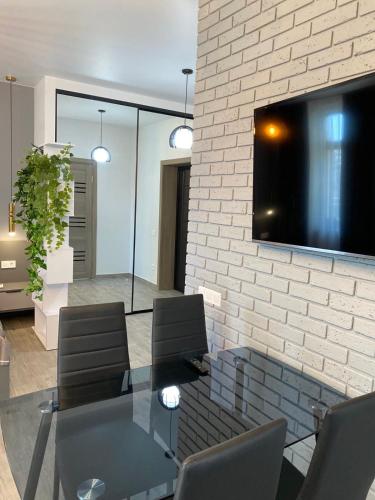 a dining room with a glass table and a tv on a brick wall at Apartments Black Sea in Odesa