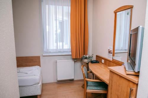a room with a desk with a television and a table with a chair at Aqua Therm Hotel in Zalakaros