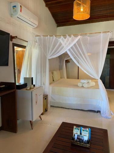 a bedroom with a bed with a mosquito net at Pousada Casa da Praia in Caraíva