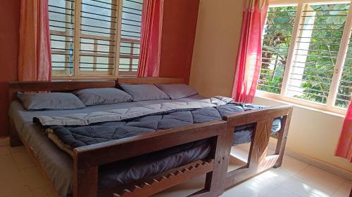 a bed sitting in a room with windows at Blue Petal Homestay in Virajpet