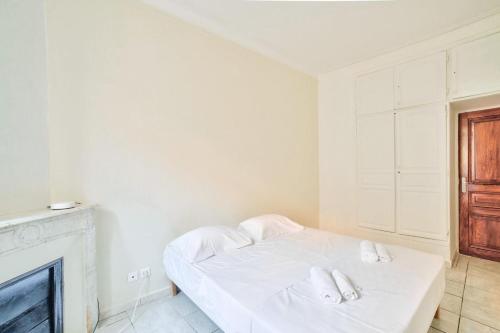 une chambre blanche avec un lit et une cheminée dans l'établissement Nidusudest - Spacieux appartement, à Nice