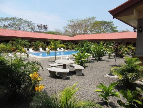 a courtyard with a picnic table and a pool at Hotel D'Lucia - Quebrada Ganado, Jaco, Costa Rica in Puntarenas