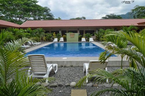 a swimming pool with two chairs and a building at Hotel D'Lucia - Quebrada Ganado, Jaco, Costa Rica in Puntarenas