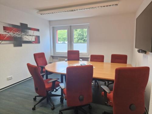 a conference room with a table and red chairs at Green Night Hotel in Falkenstein