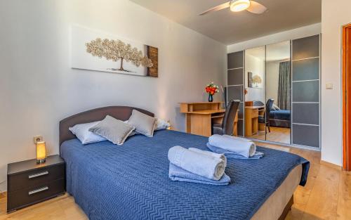 sypialnia z dużym łóżkiem z niebieskimi prześcieradłami i poduszkami w obiekcie All Seasons Apartment w Puli