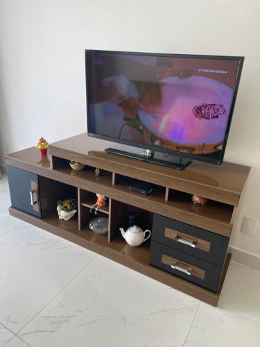 TV en un centro de entretenimiento de madera en Apt 3 Minutos Praia do Forte - Ar Condicionado, en Cabo Frío