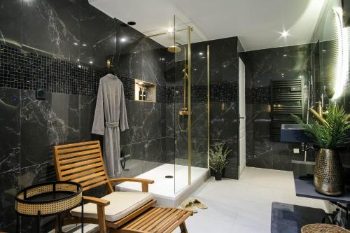 La salle de bains est pourvue d'une douche avec un banc et une chaise. dans l'établissement La Golden Suite, à Cambrai