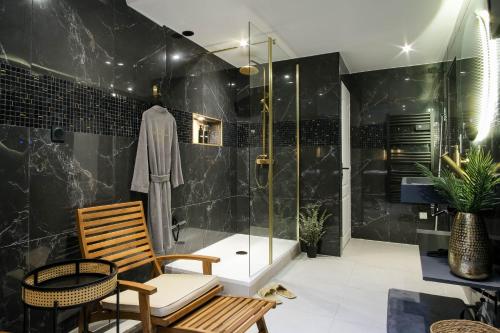 a bathroom with a shower with a bench and a chair at La Golden Suite in Cambrai
