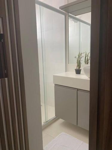 Un baño blanco con lavabo y espejo. en Confortável Apartamento em Angra dos Reis, en Angra dos Reis