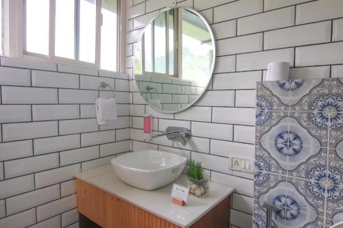 een witte badkamer met een wastafel en een spiegel bij Kaffberry Cafe & Homestays in Kūd