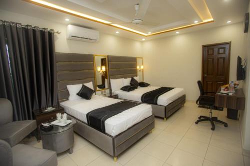 a hotel room with two beds and a desk at Hotel white season Gulberg in Lahore