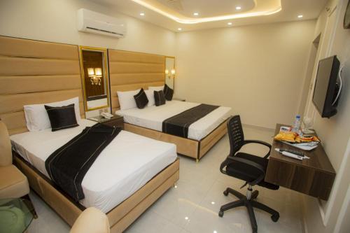 a hotel room with two beds and a desk and a chair at Hotel white season Gulberg in Lahore
