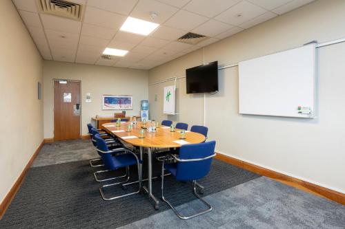 a conference room with a wooden table and blue chairs at Holiday Inn Cardiff City Centre by IHG in Cardiff