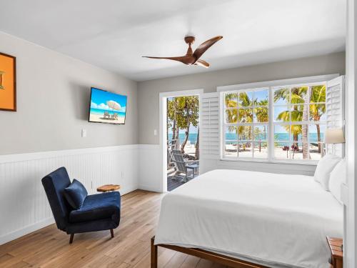 a bedroom with a bed and a chair and a window at Lime Tree Bay Resort in Islamorada