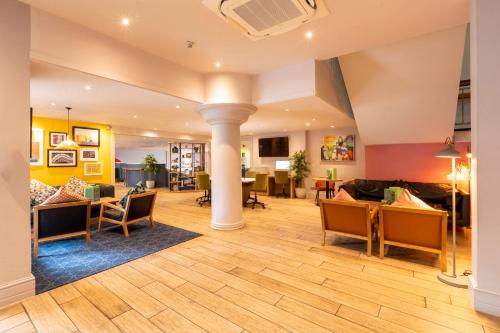 a living room with couches and tables and chairs at Holiday Inn Cardiff City Centre by IHG in Cardiff