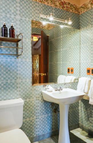 a bathroom with a sink and a toilet and a mirror at Uzhupud Garden Hotel & Lodge in Paute