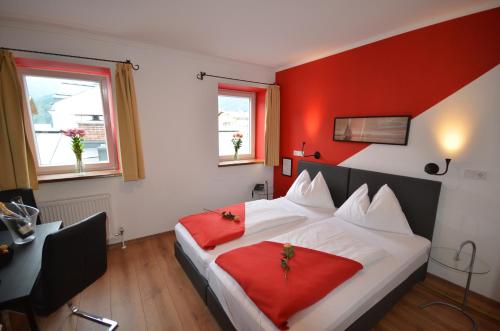 a bedroom with a large bed with red walls at Hotel Traube in Zell am See