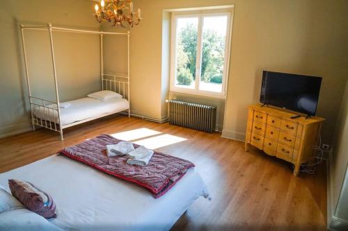 a room with a bed and a television and a table at Le Domaine du Pavillon • L'idyllique en Brenne in Nuret-le-Ferron