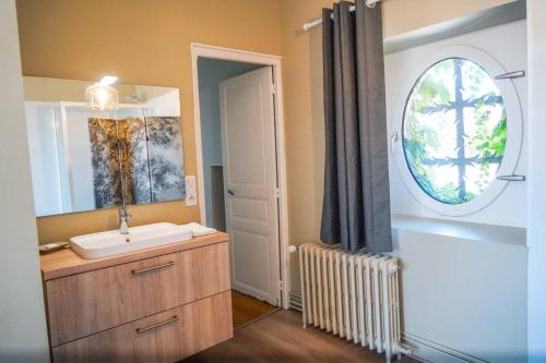 ein Bad mit einem Waschbecken, einem Spiegel und einem Fenster in der Unterkunft Le Domaine du Pavillon • L'idyllique en Brenne in Nuret-le-Ferron
