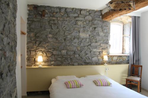 Cama en habitación con pared de piedra en Le grenier de la Floye en Biesmerée
