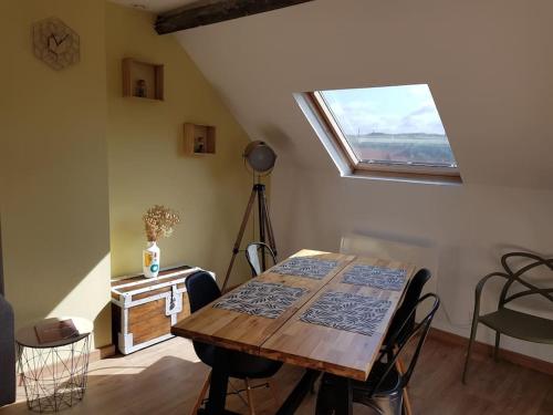 een eetkamer met een houten tafel en een raam bij Au gré du vent in Wimereux