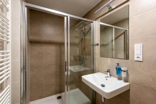 a bathroom with a shower and a sink and a mirror at Penzion Čertovy skály in Lidečko