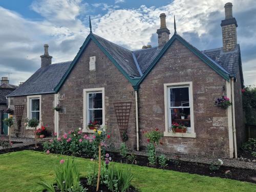 a brick house with a pitched roof at Isla Rose Cottage in Blairgowrie
