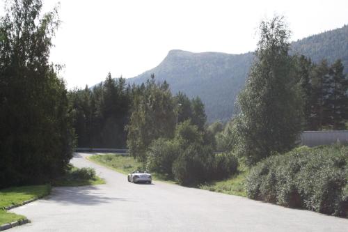 a car driving down a road with mountains in the background at Dovreskogen Gjestegård AS in Dovreskogen